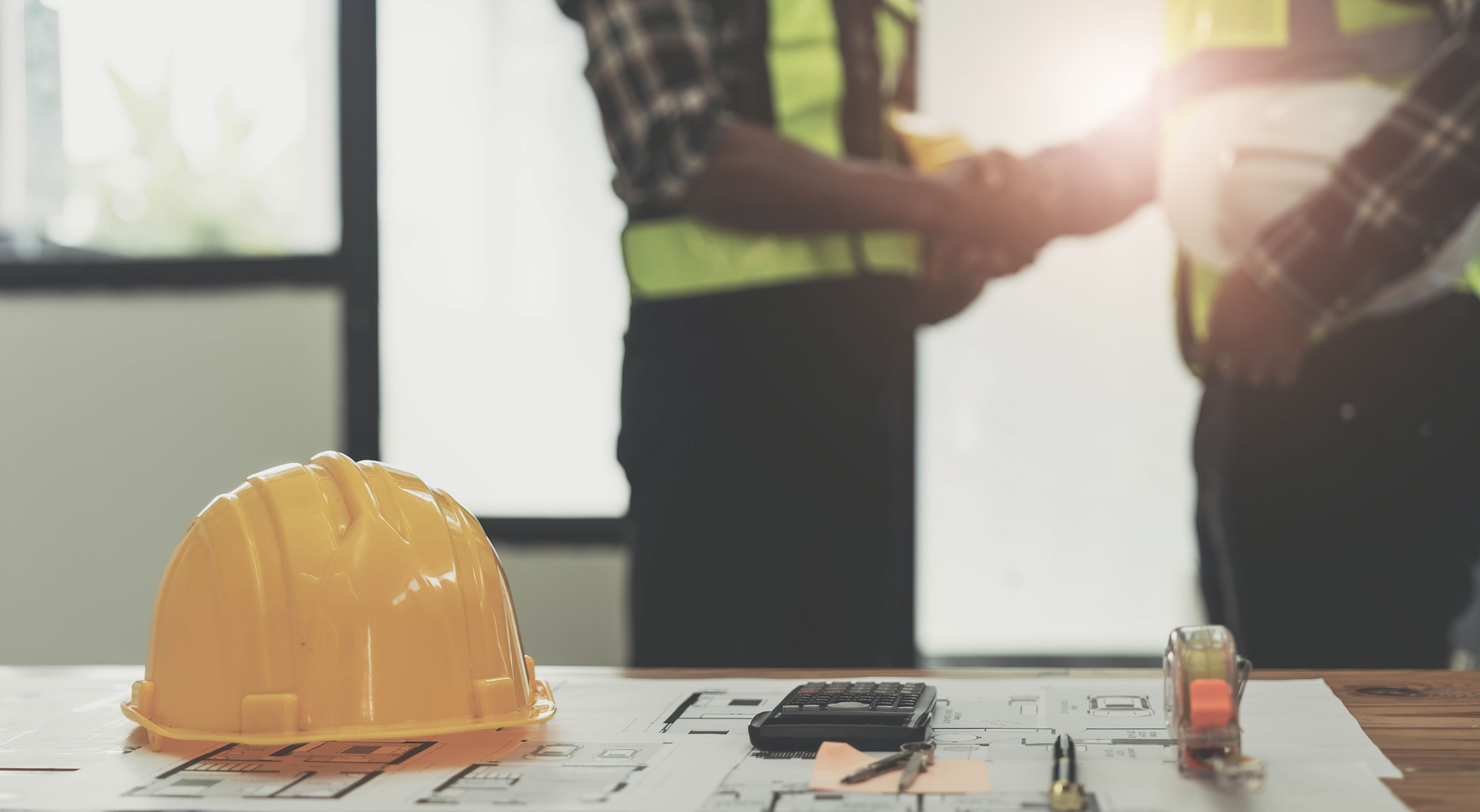 yellow safety helmet on workplace desk with construction worker